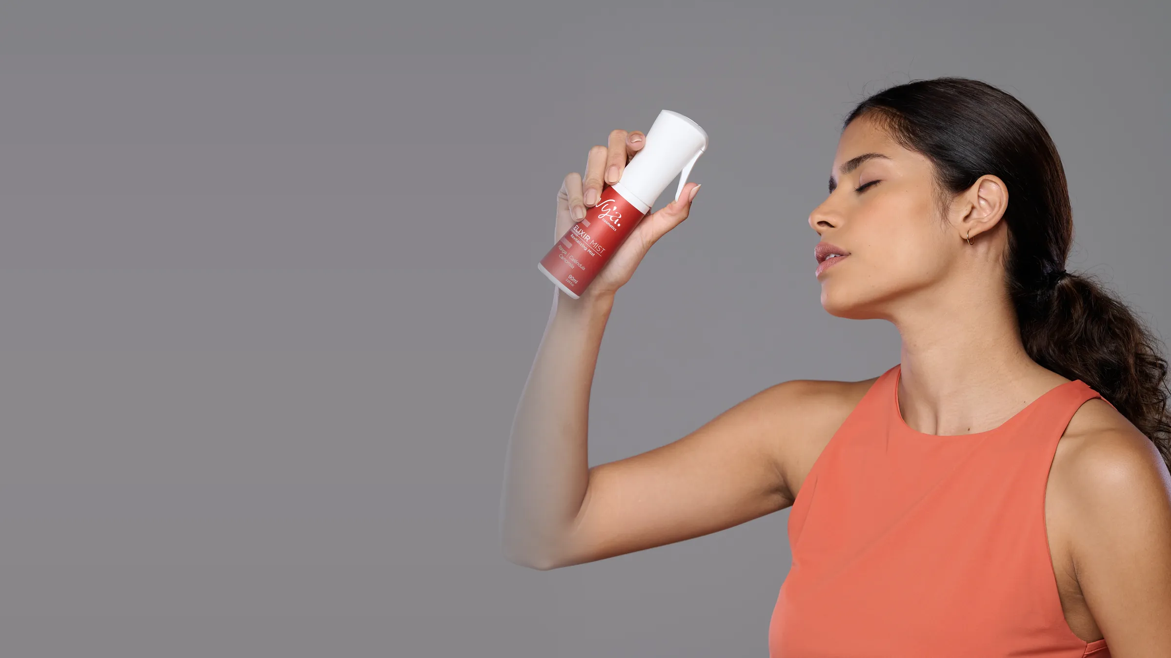 Modelo com o Sérum Vitamina C junto ao rosto, de olhos fechados: o antioxidante da manhã