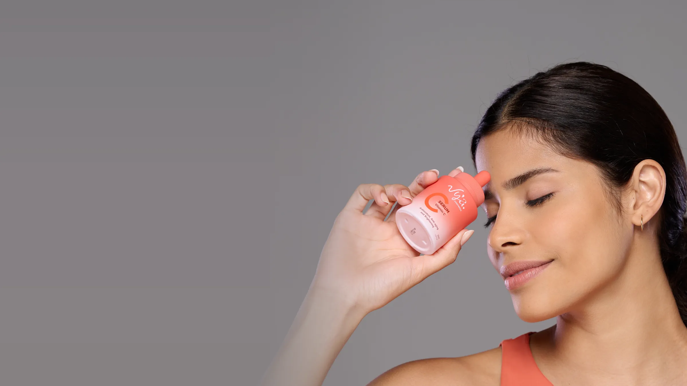 Pipeta com a fórmula branco-marfim do Sérum Vitamina C, frasco na mão da modelo