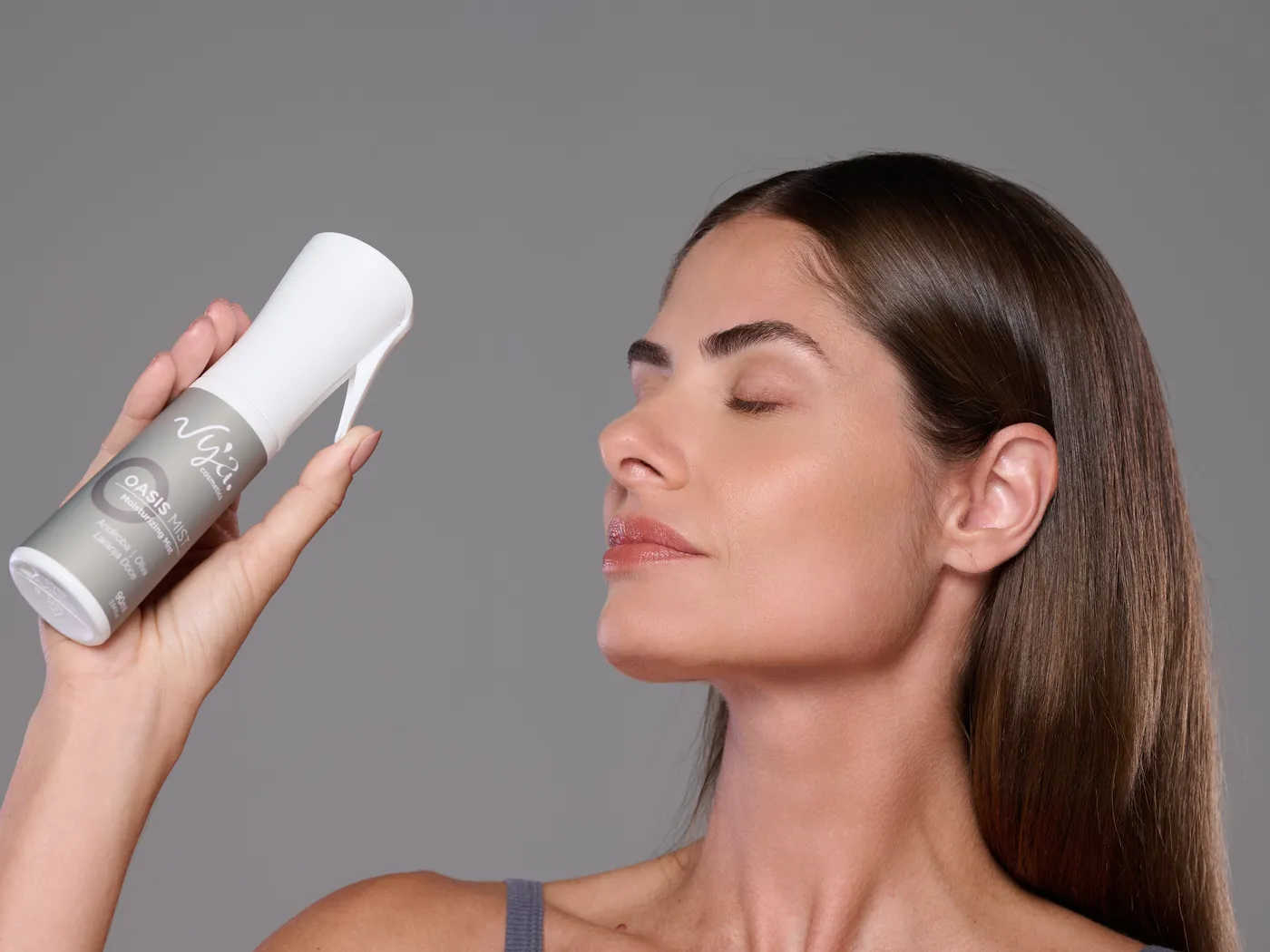 Modelo borrifa o Oasis Mist a distância do rosto, de olhos fechados. Marcação da névoa e dos 30 cm.